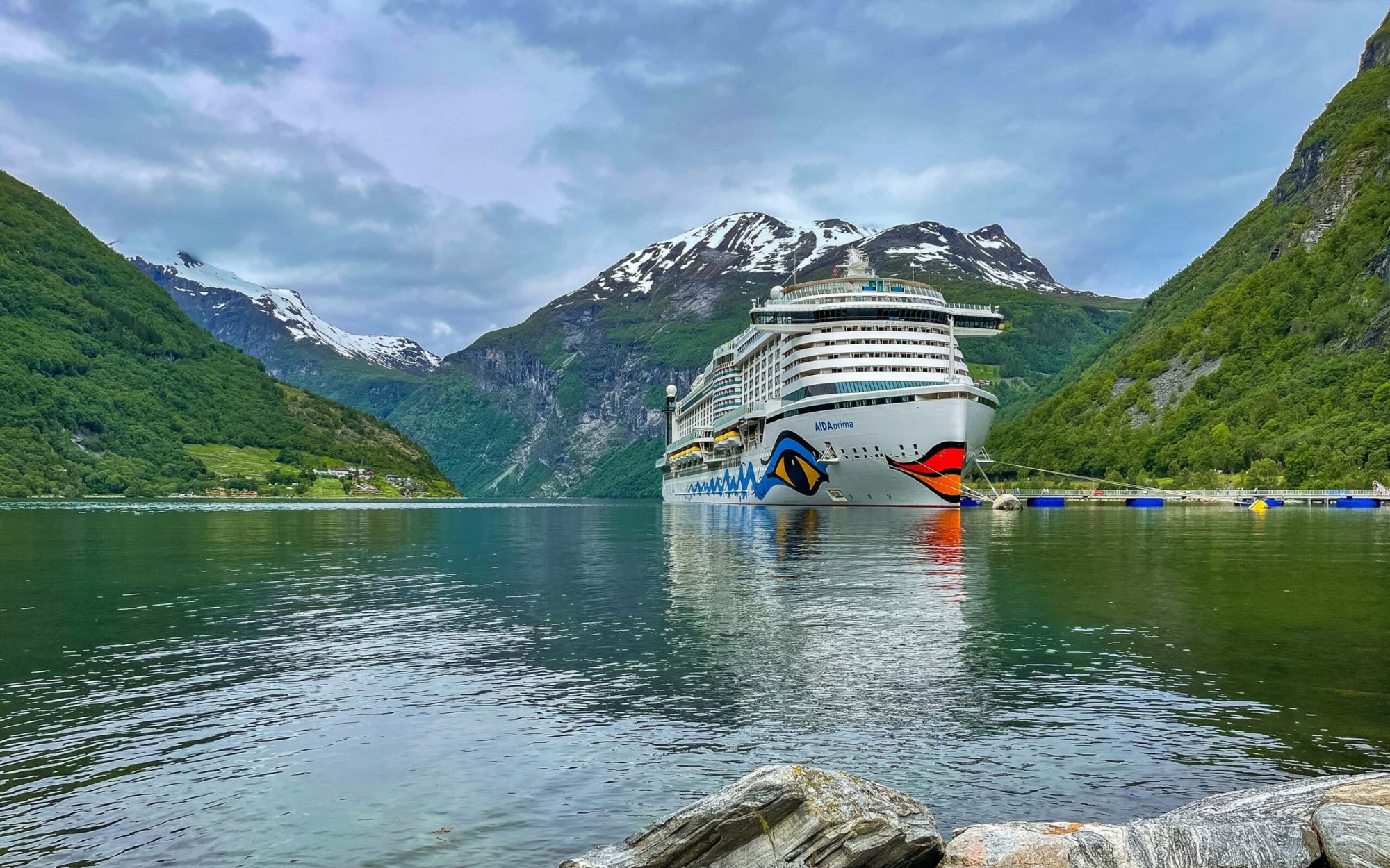 AIDAperla Kreuzfahrtschiff in einem norwegischen Fjord mit Wasserfall und steilen Felswänden