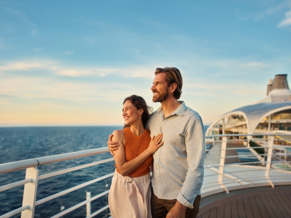 Paar genießt den Sonnenuntergang an Deck der Mein Schiff mit Blick auf das offene Meer